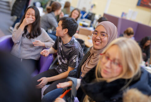 A group of students chatting and laughing in the Global Room
