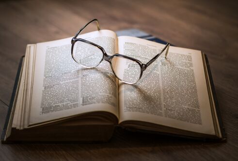 photograph of an open book with glasses placed on top