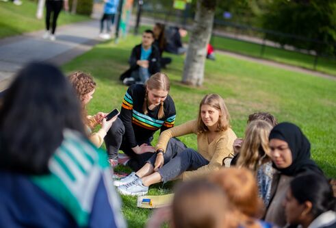 Student sat on the grass at welcome week on campus 