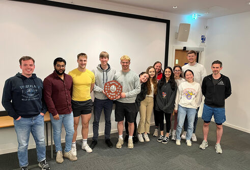 A group of students lined up in a row with one person holding a trophy
