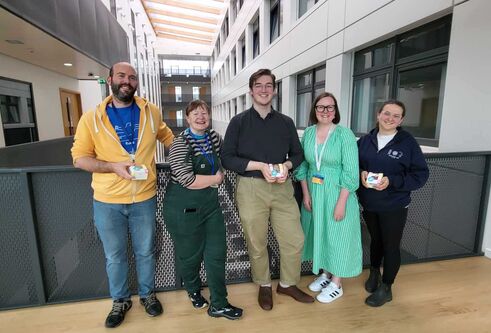 Five people stand on an upper floor of the Life Sciences building, with their backs to a barrier.