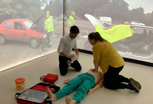 A demonstration of CPR in the Immersion Room, with car crash scene projected in the background