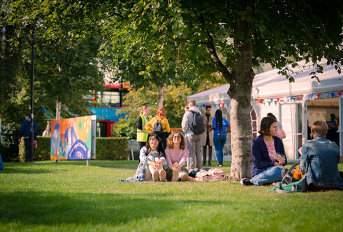 Students sitting on grass at campus green
