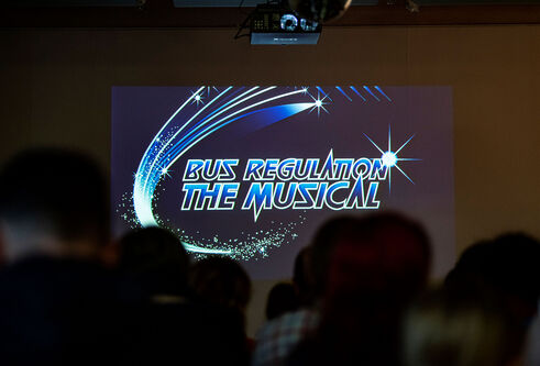 Bus regulation photo showing on a stage in the background 