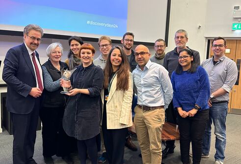 A group of people acceptin an award in front of a projector screen