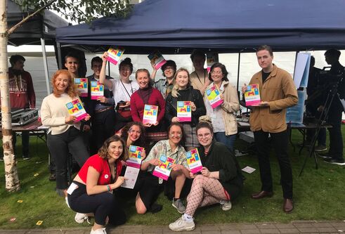 students at a stall holding magazine copies
