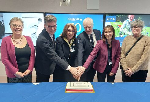 University and NHS Tayside executives cut a cake