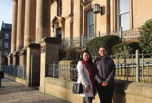 two students outside a stone building with pillars