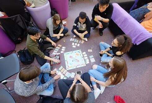 students sitting around a monopoly board