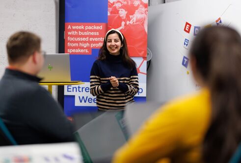 A woman confidently presenting to a group of attentive individuals during a professional meeting.