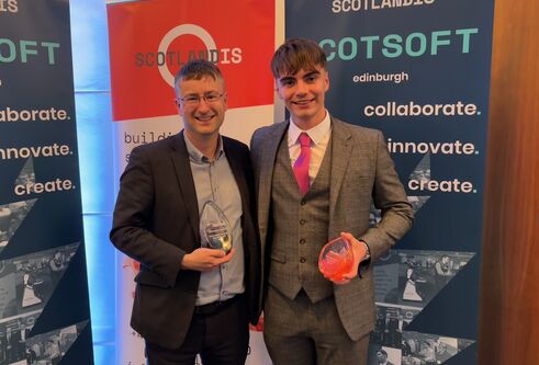 Mike Crabb with David Topping at the ceremony, holding his award before a branded backdrop