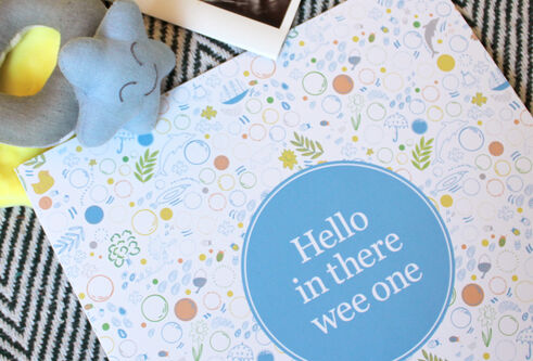 The cover of "Hello In There Wee One", a photo of a baby scan and a baby's rattle