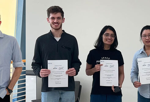 Four people stood smiling. Three holding certificates.