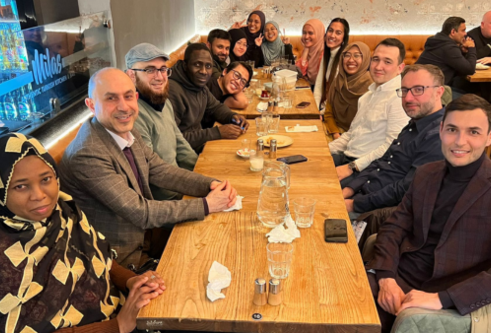 A large group of people sit around a table in a restaurant