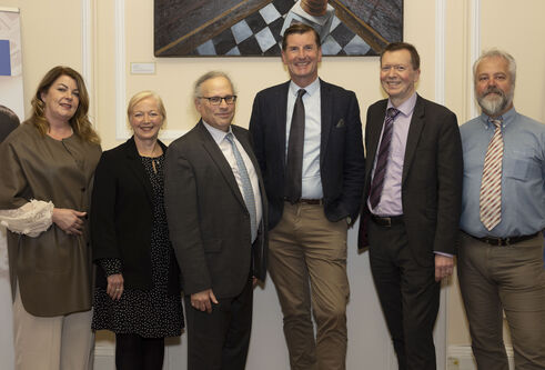 Six smartly dressed people stand in a line looking frowards.