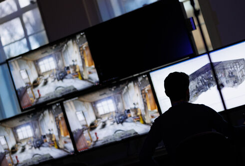 Vincenzo Rinaldi sits in front of several computer monitors showing virtual reality reconstructions of crime scenes