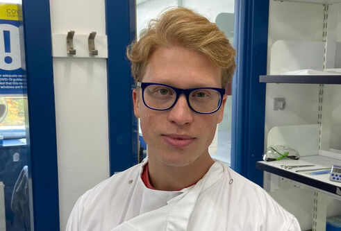 A head and shoulders photo of a man in a lab wearing a lab coat