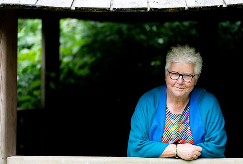 Val McDermid in a blue cardigan and striped, multi-coloured top, smiling