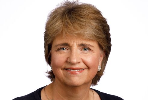 close up head and shoulders image of woman with short fair hair, smiling at camera