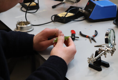 Undergraduate engineering student at the University of Dundee building components for PCB in a laboratory setting.
