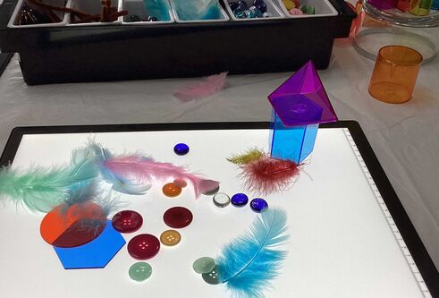 A lightbox with colourful buttons and feathers on top.
