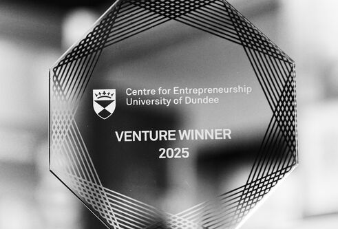 A black and white image of a Venture 2025 trophy, close-up