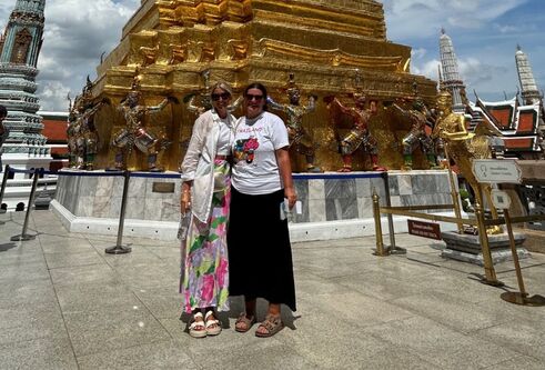 Two women stand in front of a large gold statue
