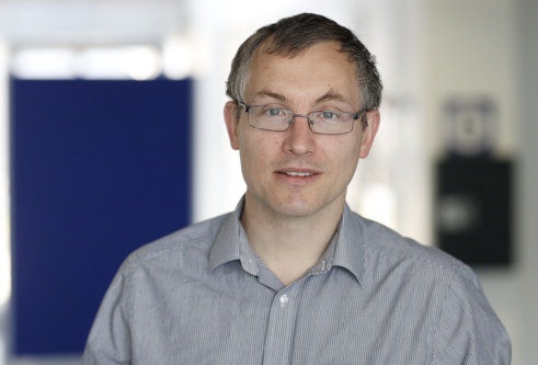 Professor James Chalmers, wearing a grey shirt and glasses in a medical setting