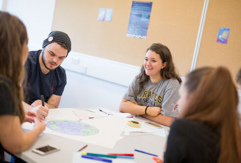 Group of students sitting at a table studying and chatting together
