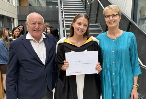Three people stood next each other, one holding a certificate