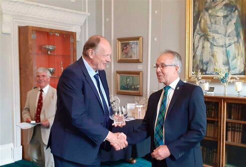 Two men wearing suits shake hands.