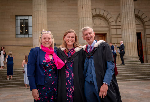 a group of three stood outside smiling