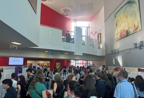 A crowd of people all stood together in a foyer with an overlooking mezzanine level above