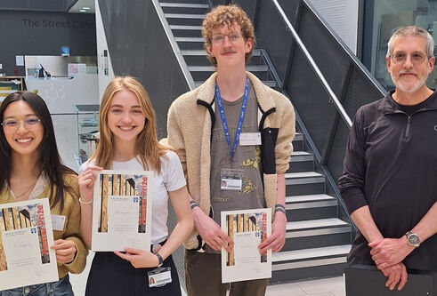 Four people stood smiling. Three holding certificates.