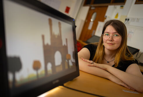 Young woman with dark hair shown to the side of a computer screen with a graphic of an arch on it