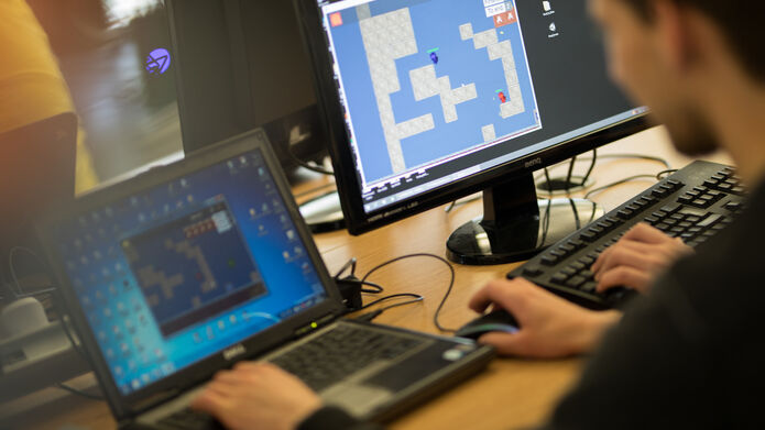a person on a laptop playing a game that is showing on the screen