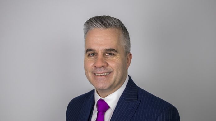 greg in a suit smiling