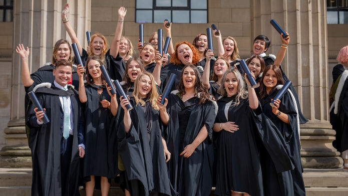 A group of recent graduates celebrate on the steps of the Caird Hall
