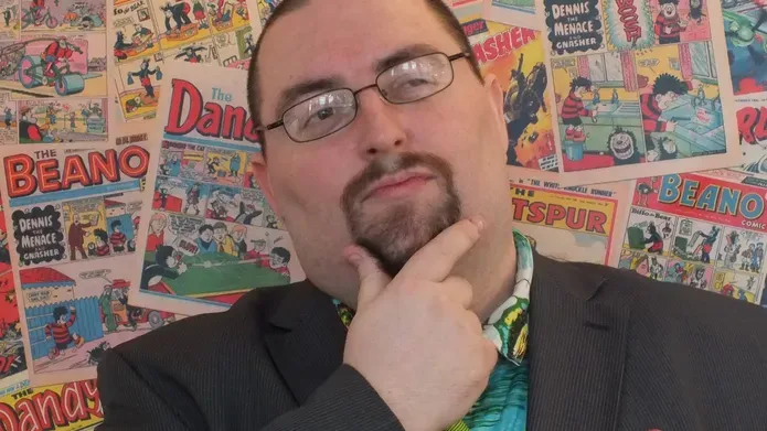 Chris Murray in front of a wall of comics