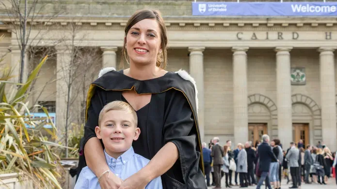 Charlotte in a graduation gown with her son in front of Caird Hall