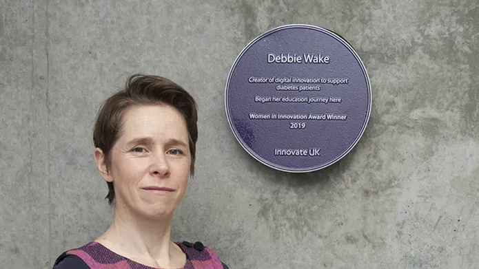 Debbie Wake standing next to her plaque