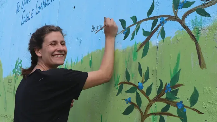 Alexis Bernstein painting a garden mural
