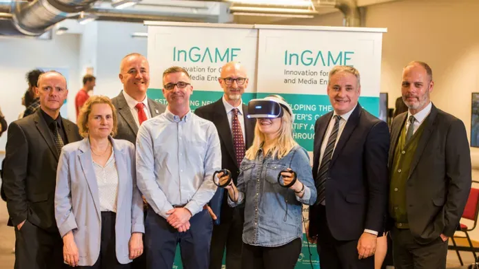 A group of people, one of whom is wearing a VR headset