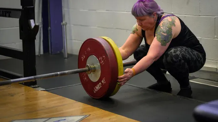 Irene Hallyburton puts weights on a bar