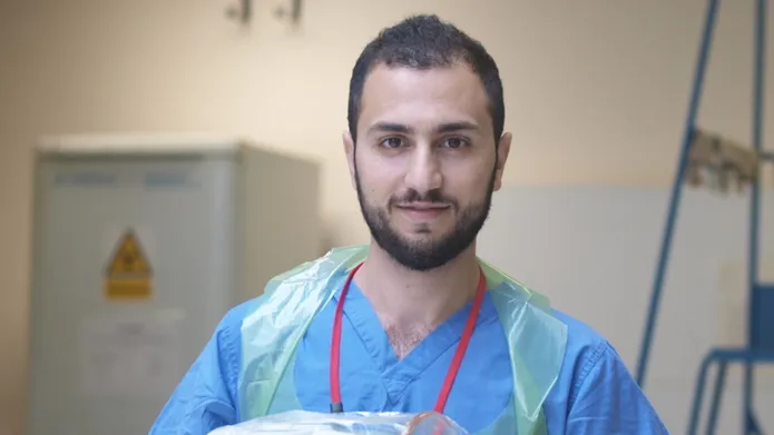 Rawad Qaq in scrubs with an apron on