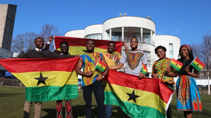 Students with ghana flags infront of blue sky