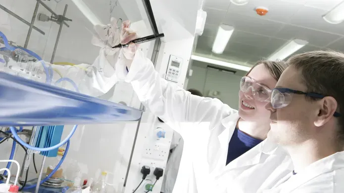 people in PPE writing on a transparent surface with permanent marker
