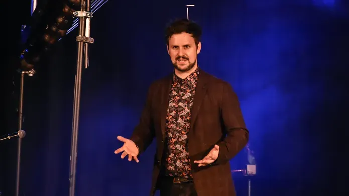 Kevin Quantum standing with his palms facing upwards and smiling