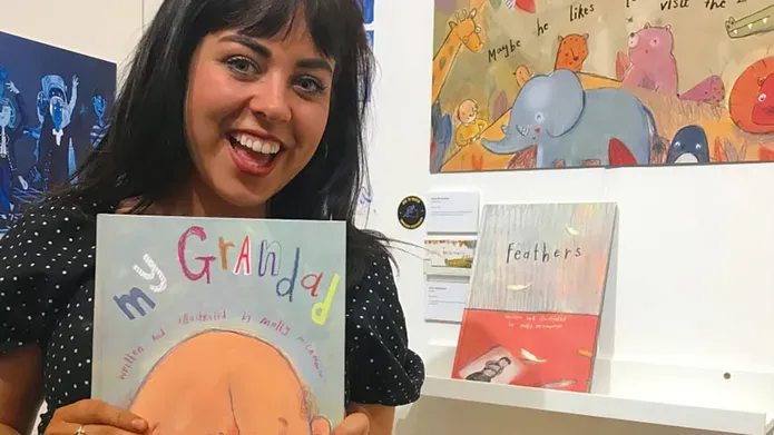 Molly holding the book she illustrated called My Grandad