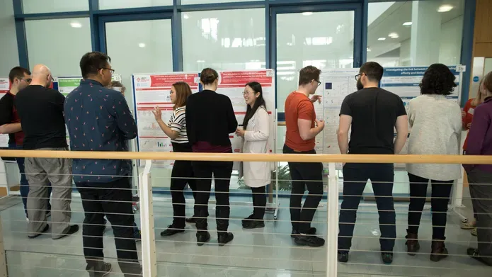 group of people looking at a poster on a glass wall